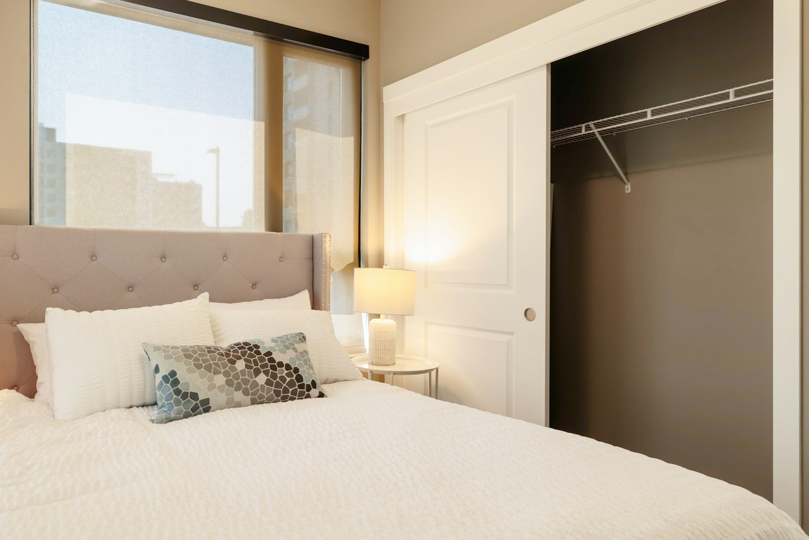 Bedroom with tufted headboard and open closet.